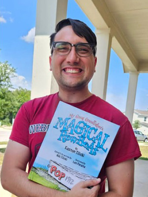 Author, Easton Tilicki, posing with copy of book